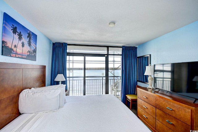 bedroom featuring carpet, a textured ceiling, access to outside, and expansive windows