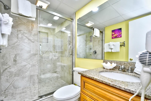 bathroom featuring a shower with door, vanity, and toilet