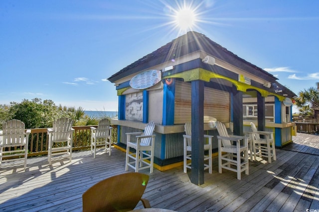 wooden deck featuring a water view, a bar, and a gazebo