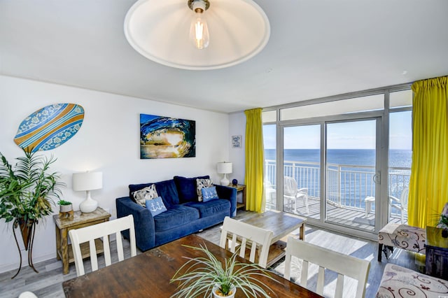 living room with a wall of windows, a water view, and hardwood / wood-style flooring