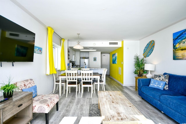 living room with crown molding and light wood-type flooring