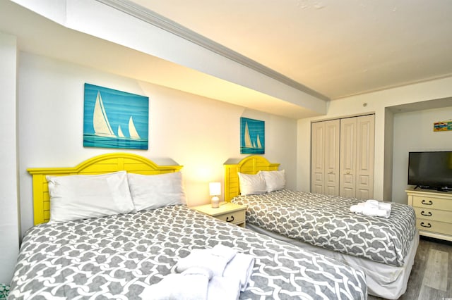 bedroom featuring hardwood / wood-style flooring, crown molding, and a closet