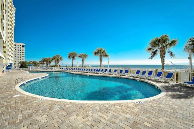 view of swimming pool featuring a water view and a patio