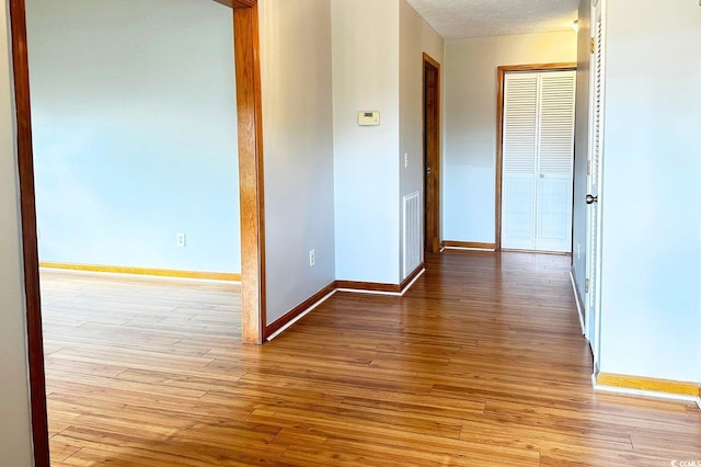 corridor with a textured ceiling and light wood-type flooring