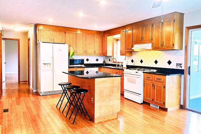 kitchen with a center island, light hardwood / wood-style floors, white appliances, and sink