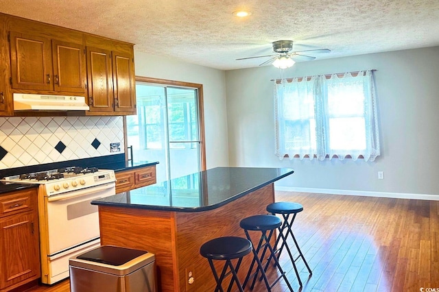 kitchen featuring a center island, hardwood / wood-style flooring, plenty of natural light, and white gas range