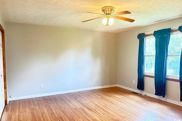 unfurnished room with ceiling fan, light wood-type flooring, and a textured ceiling