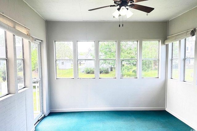 unfurnished sunroom featuring ceiling fan and a healthy amount of sunlight