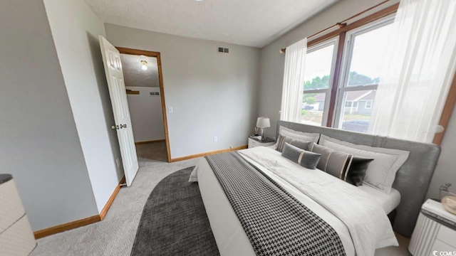 bedroom with light colored carpet and a textured ceiling