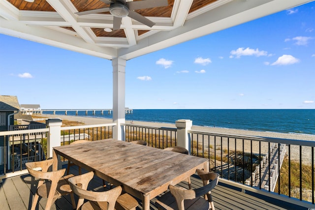 deck with ceiling fan, a water view, and a beach view