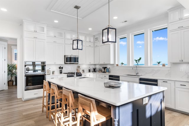 219 S Seaside Dr, Surfside Beach, SC 29575 - kitchen with appliances with stainless steel finishes, light wood-style flooring, tasteful backsplash, white cabinets, and a kitchen bar