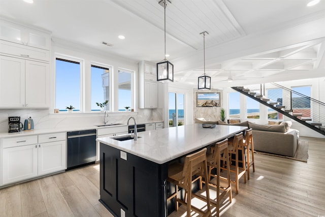219 S Seaside Dr, Surfside Beach, SC 29575 - kitchen featuring dishwashing machine, light wood-style flooring, a center island with sink, decorative backsplash, and beam ceiling