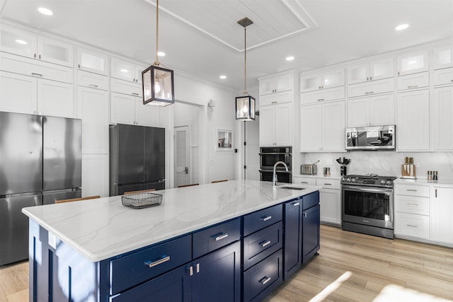 kitchen featuring blue cabinetry, decorative light fixtures, stainless steel appliances, and an island with sink