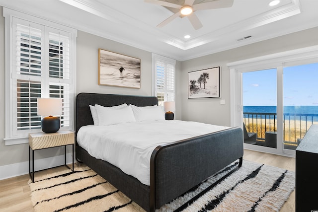 219 S Seaside Dr, Surfside Beach, SC 29575 - bedroom featuring ornamental molding, access to outside, light wood finished floors, a raised ceiling, and a water view