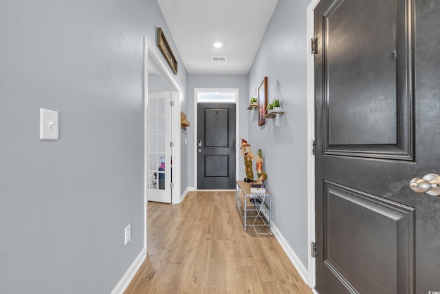 corridor with light hardwood / wood-style flooring and french doors