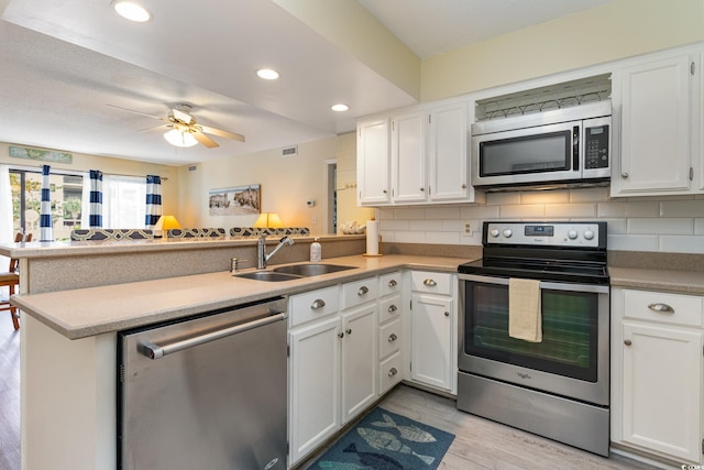 kitchen featuring white cabinetry, sink, stainless steel appliances, light hardwood / wood-style flooring, and kitchen peninsula