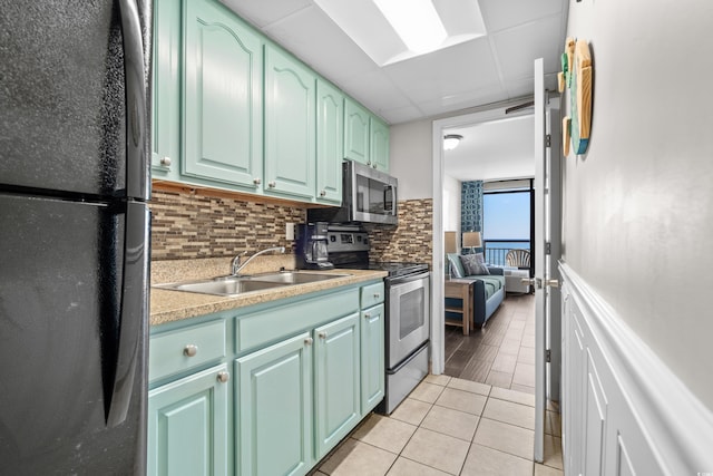 kitchen with backsplash, light tile patterned floors, sink, and appliances with stainless steel finishes