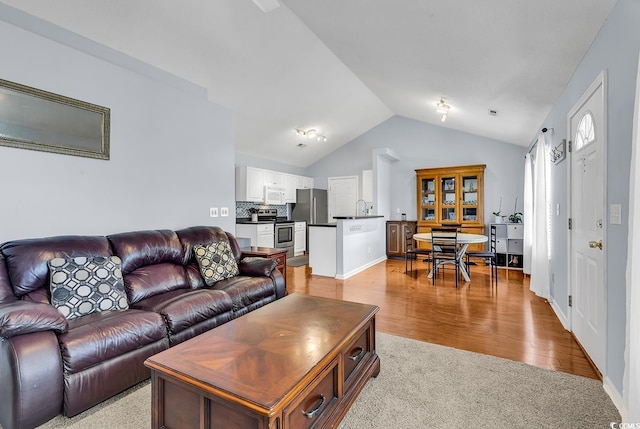 carpeted living room featuring lofted ceiling and sink