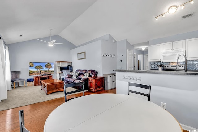 dining room featuring hardwood / wood-style floors, vaulted ceiling, and ceiling fan