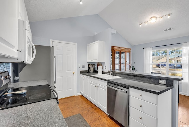 kitchen featuring dishwasher, range, vaulted ceiling, and white cabinetry