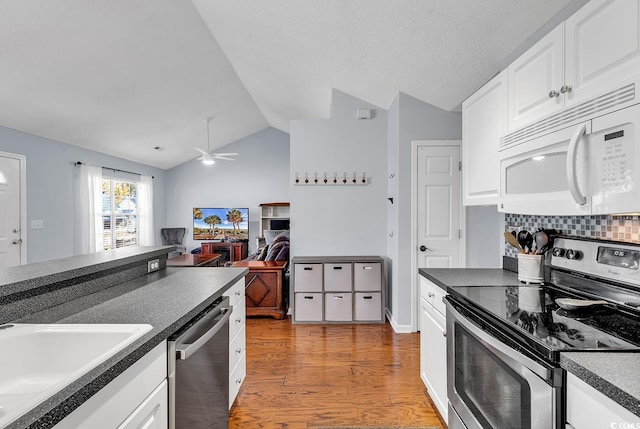 kitchen with lofted ceiling, white cabinets, light hardwood / wood-style flooring, ceiling fan, and appliances with stainless steel finishes