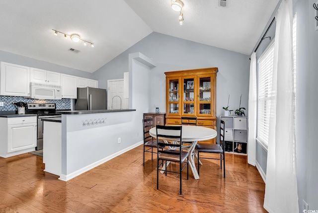 dining space featuring light hardwood / wood-style flooring and lofted ceiling