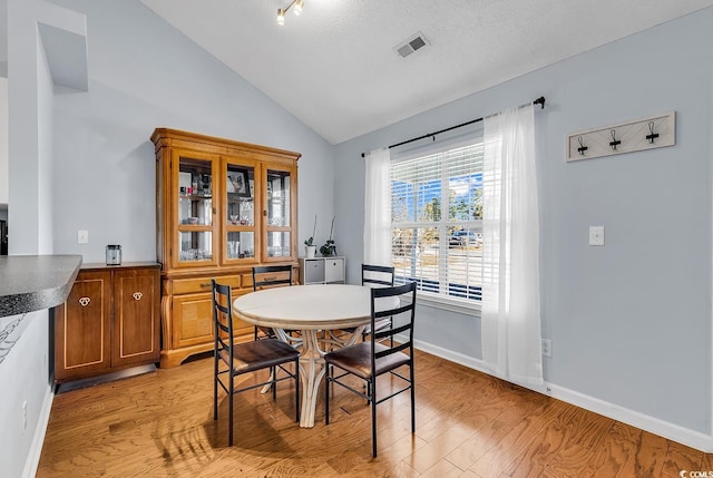 dining room with light wood-type flooring and lofted ceiling