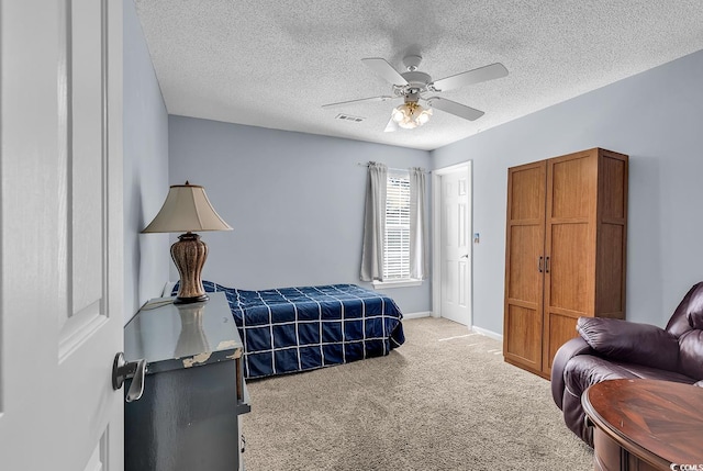 bedroom with ceiling fan, light carpet, and a textured ceiling