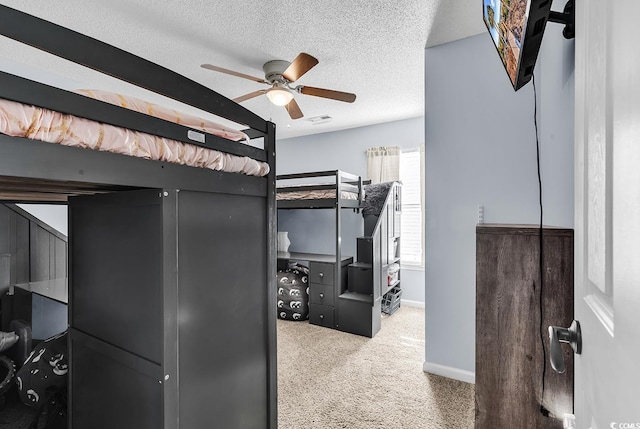 bedroom featuring ceiling fan, light carpet, and a textured ceiling