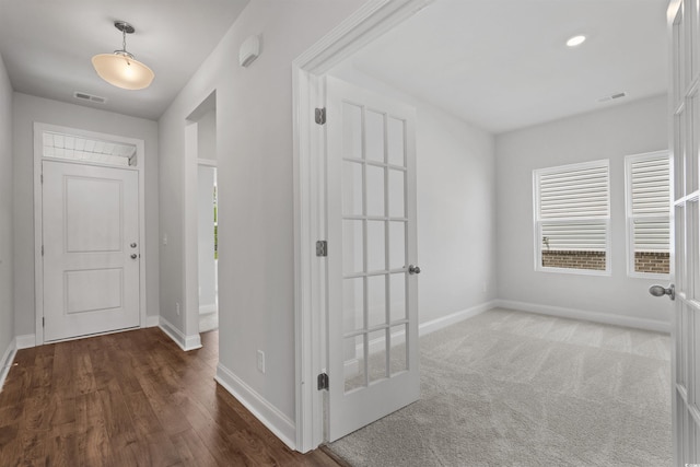 foyer with wood finished floors, visible vents, and baseboards
