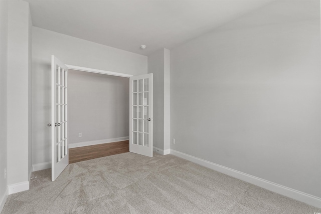 carpeted spare room featuring baseboards and french doors