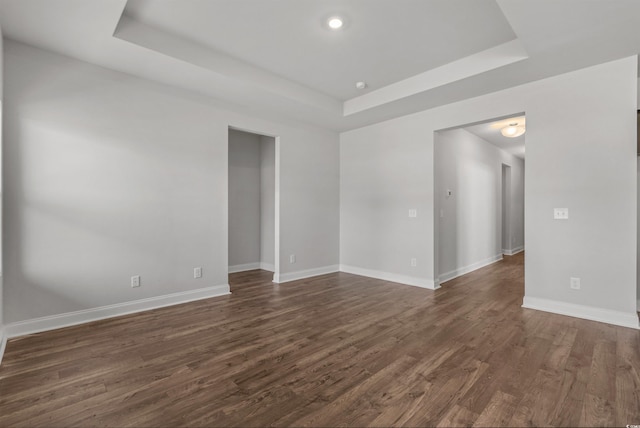 spare room with dark wood-type flooring, recessed lighting, baseboards, and a tray ceiling
