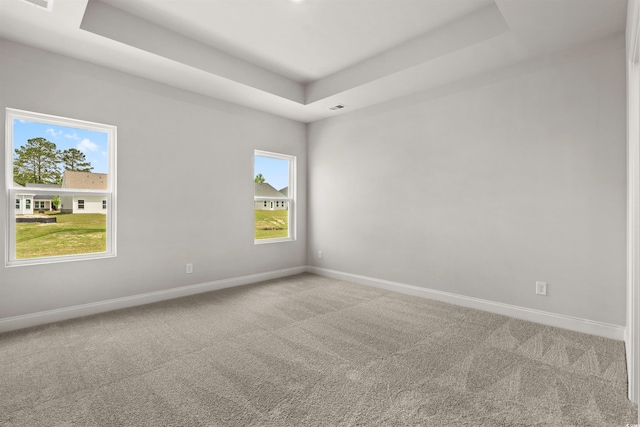 carpeted empty room with a tray ceiling and baseboards