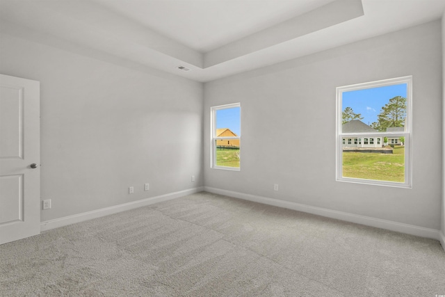 empty room featuring baseboards, visible vents, a raised ceiling, and carpet