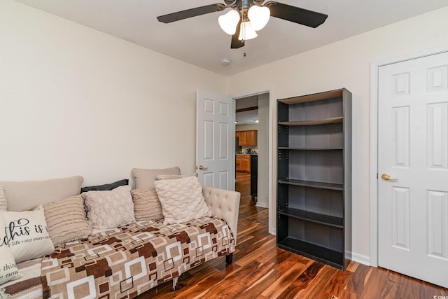 living room with built in shelves, ceiling fan, and dark wood-type flooring