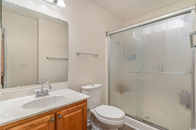 bathroom featuring vanity, toilet, and a shower with door