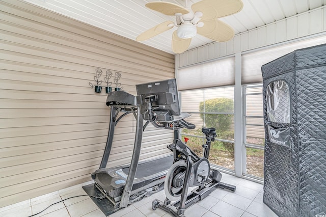 workout area featuring wood walls, light tile patterned floors, and ceiling fan