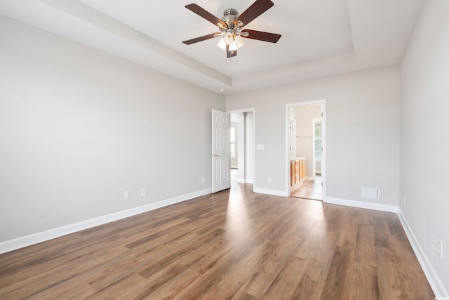 unfurnished room with hardwood / wood-style floors, ceiling fan, and a tray ceiling