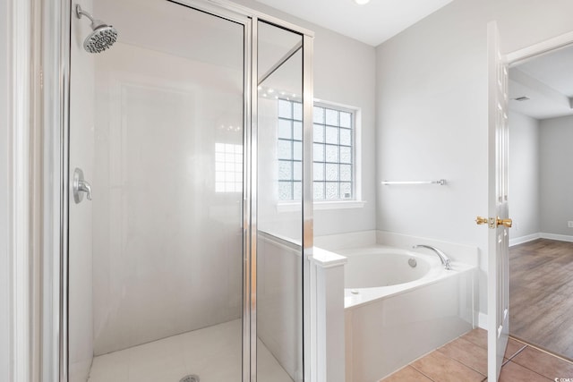 bathroom featuring plus walk in shower and hardwood / wood-style flooring