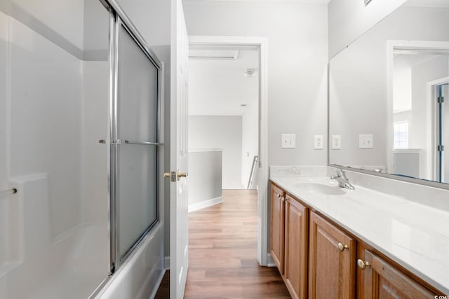 bathroom with hardwood / wood-style flooring, vanity, and enclosed tub / shower combo