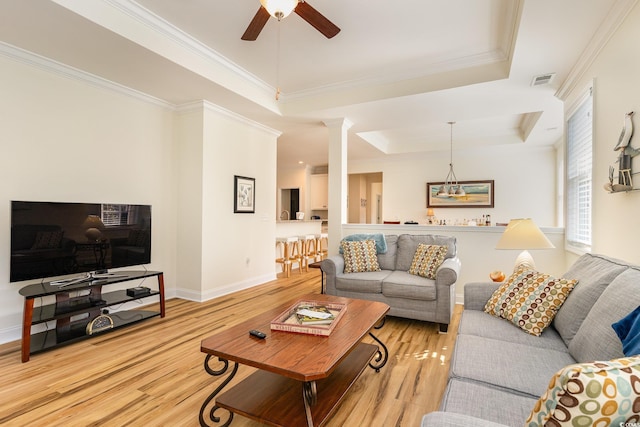 living room with a tray ceiling, crown molding, light hardwood / wood-style flooring, and ceiling fan