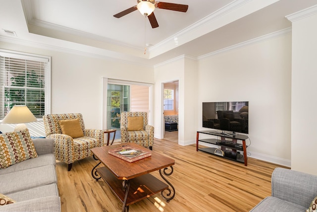 living room with a raised ceiling, ceiling fan, hardwood / wood-style floors, and ornamental molding