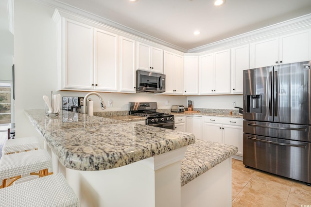 kitchen with white cabinets, light stone countertops, kitchen peninsula, and appliances with stainless steel finishes