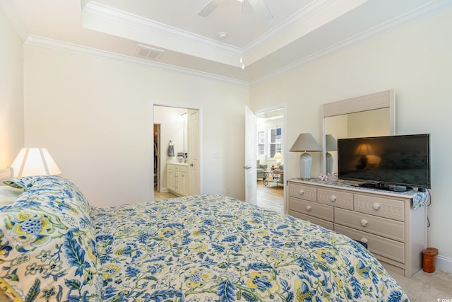 bedroom with ceiling fan, a raised ceiling, crown molding, ensuite bathroom, and light colored carpet