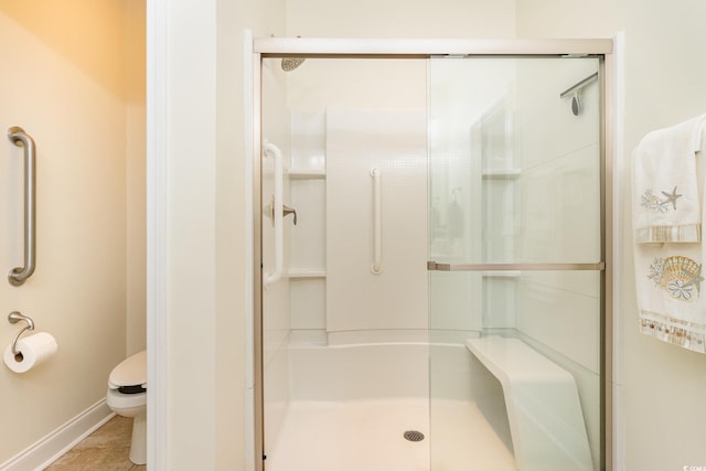 bathroom featuring tile patterned floors, toilet, and a shower with shower door