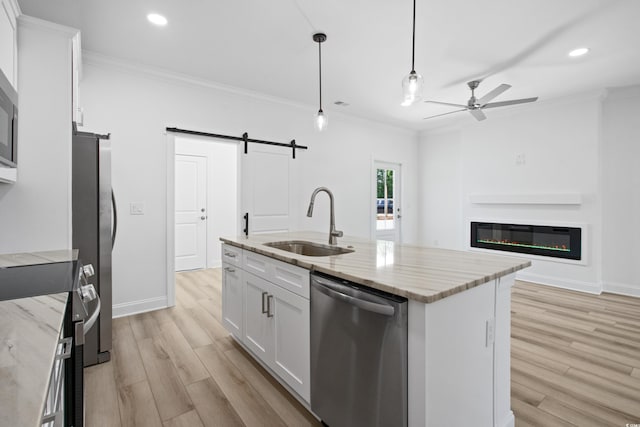 kitchen featuring pendant lighting, a kitchen island with sink, sink, appliances with stainless steel finishes, and white cabinetry