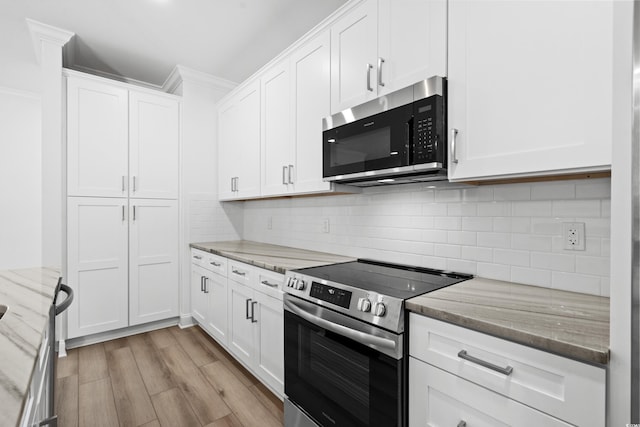 kitchen with appliances with stainless steel finishes, light hardwood / wood-style floors, white cabinetry, and light stone counters