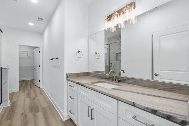 bathroom with hardwood / wood-style floors, vanity, and walk in shower