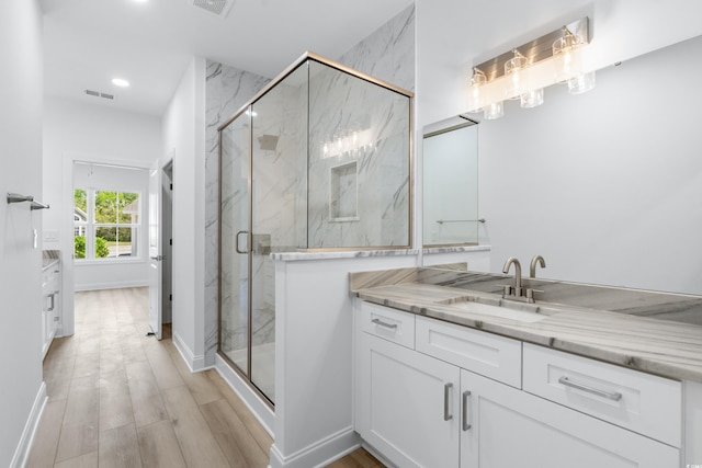 bathroom featuring hardwood / wood-style floors, vanity, and a shower with shower door