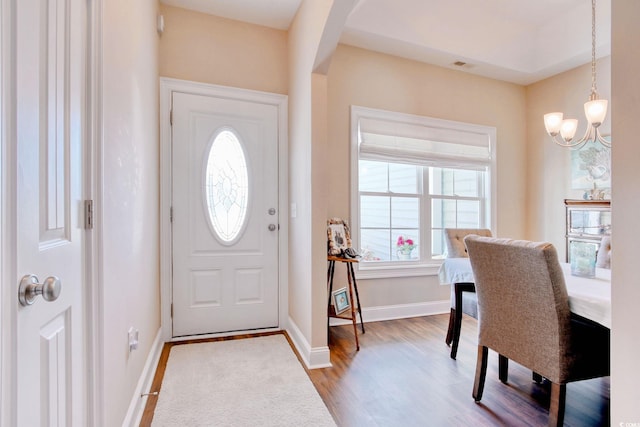 foyer with a chandelier, wood-type flooring, and plenty of natural light